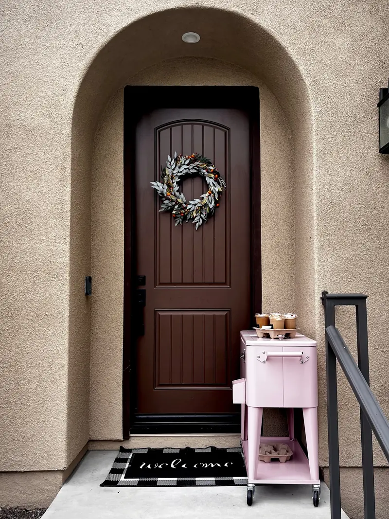 The Caffinnate café cart, a small pink cart set up by a front door